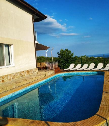 a swimming pool with chairs and a building at Villa Meraki in Byala