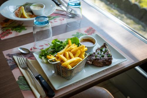 a plate of steak and french fries on a table at Campanile Rouen Sud - Zénith - Parc Expo in Saint-Étienne-du-Rouvray