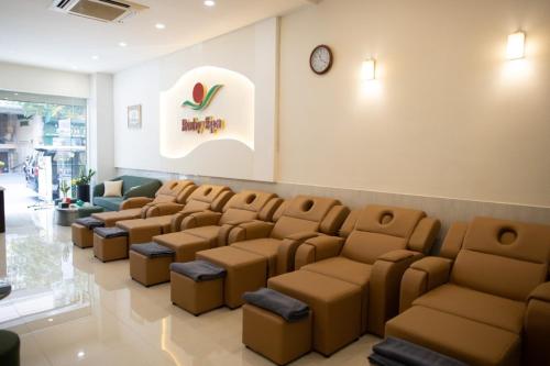 a waiting room with brown chairs and a clock on the wall at Ruby Hotel in Ho Chi Minh City