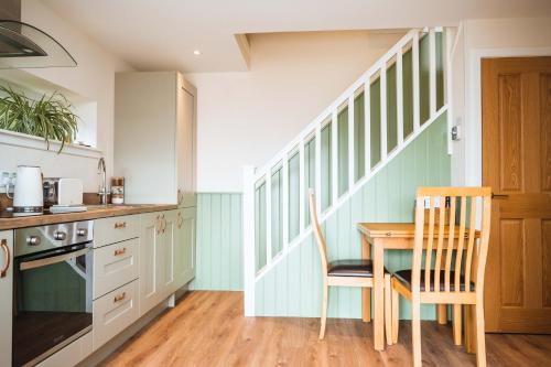 a kitchen with a table and chairs and a staircase at Taighsona Bothy, Speyside - amazing views! in Archiestown