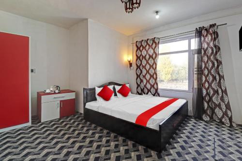 sypialnia z łóżkiem z czerwonymi poduszkami i oknem w obiekcie Eco Rooms w mieście Jawāharnagar