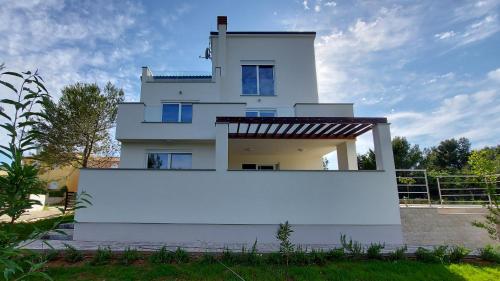a white house with a white wall in front of it at Villa Mare in Ližnjan