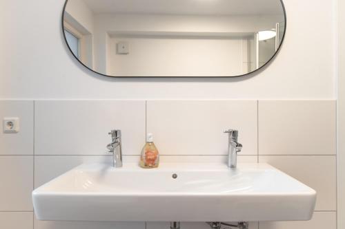 a white sink in a bathroom with a mirror at Ferienwohnungen Galerie im Klink in Quedlinburg