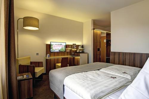 a hotel room with a bed and a television at Hotel Am Badepark in Bad Zwischenahn