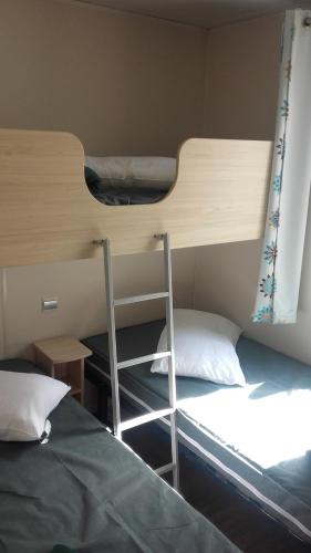two bunk beds in a dorm room with a ladder at La Perle du Littoral in Vias