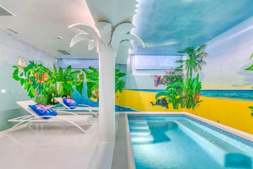 a room with a pool with a palm tree mural at The Pink Elephant Hotel in S'Agaro