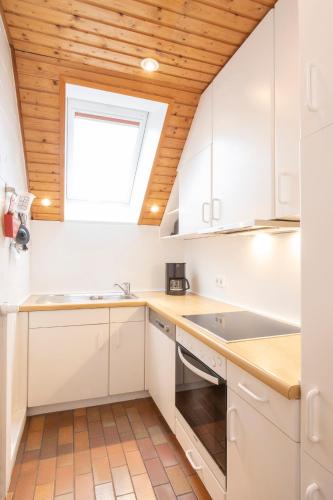 a kitchen with white cabinets and a window at Kettelhack Appartement -K4a- im KETTELHACK in Langeoog