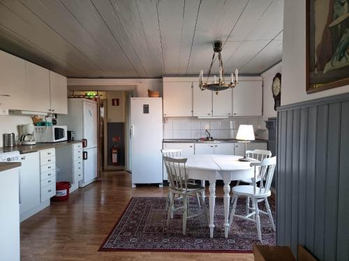 a kitchen with a white table and chairs in it at Kobbar & Skär Vandrarhem in Ellös