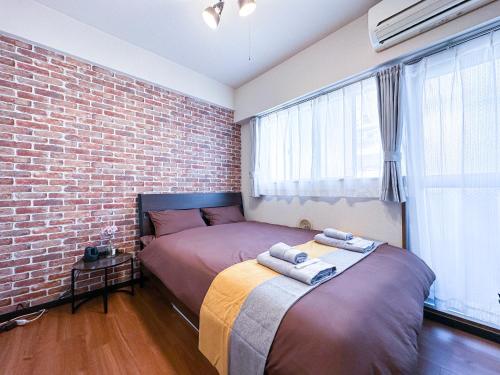 a bedroom with a bed and a brick wall at nestay apartment tokyo ikebukuro in Tokyo