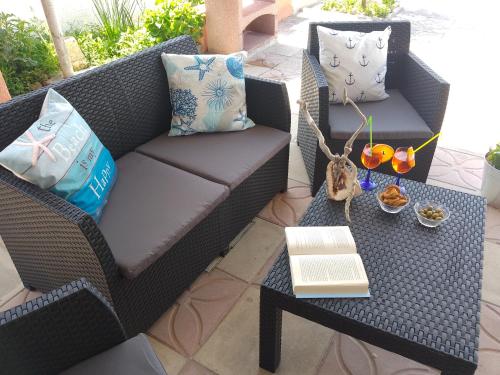 a patio with a couch and a table with a book at Villino Il melograno in Torre Specchia Ruggeri