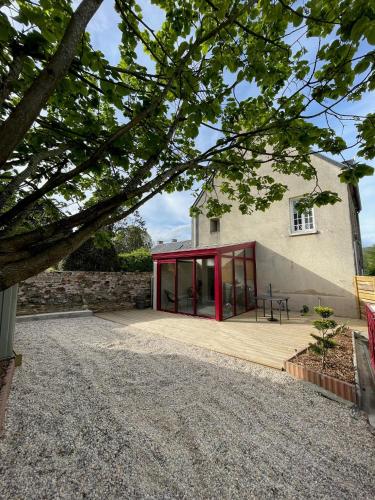 a house with red doors and a wooden patio at Le Marlo in Poilley