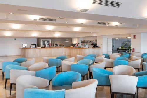 a waiting room with blue chairs and a bar at AluaSun Doblemar in La Manga del Mar Menor
