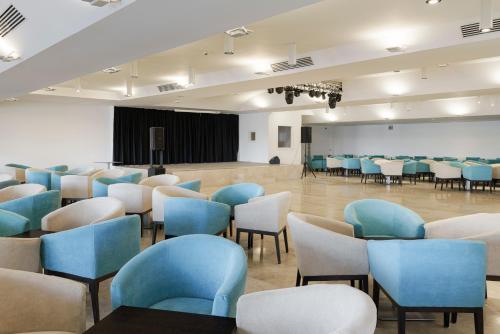 a room with blue chairs and tables and a stage at AluaSun Doblemar in La Manga del Mar Menor