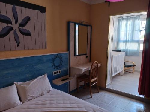 Un dormitorio con una cama, un escritorio y un espejo. en L'Ocell Blau, en Miami Platja