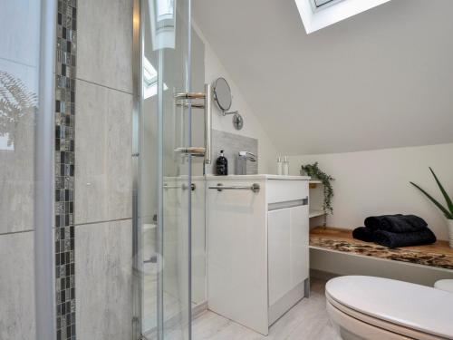 a white bathroom with a shower and a toilet at Abode in Axminster