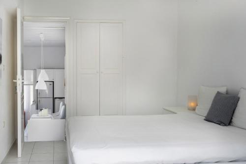 a white bedroom with a large white bed and a bathroom at Konstantinos and Eleni's Apartment in Koundouros