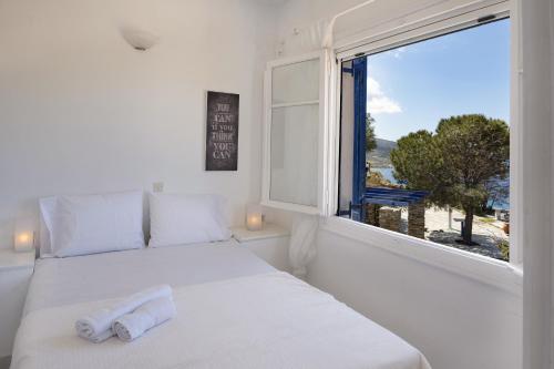 a white bedroom with a bed and a window at Konstantinos and Eleni's Apartment in Koundouros