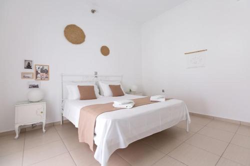 a white bedroom with two beds and a night stand at Sorocada Private House in Akrotiri