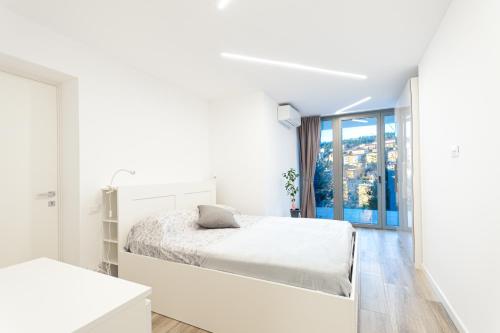 Casa vacanze Montebello في ترييستي: غرفة نوم بيضاء بها سرير ونافذة