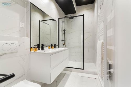 une salle de bain blanche avec un lavabo et une douche dans l'établissement King Size beds - Zen Monceau, à Paris