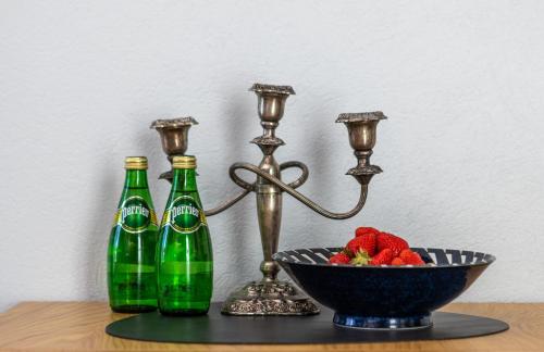 un tavolo con due bottiglie e una ciotola di fragole di GENIO 7 apartamentai a Palanga