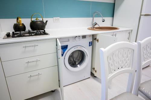 a kitchen with a washing machine and a sink at Светлая двухкомнатная квартира с Wi-Fi стильный дизайн и всё необходимое in Aktobe