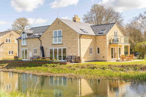 a house with a pond in front of it at Fletland Mill and Holiday Hamlet - 18th century watermill, in stunning location near Stamford in Stamford