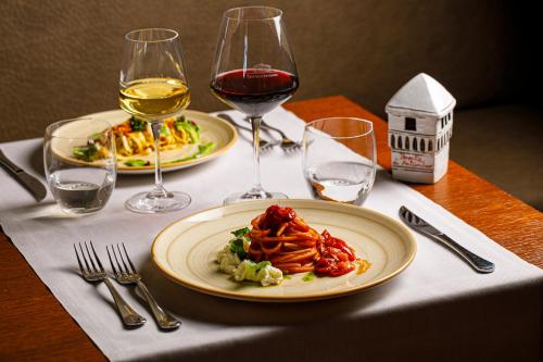 a table with two plates of food and glasses of wine at Tenuta di Artimino member of Meliá Collection Wine Resort in Artimino