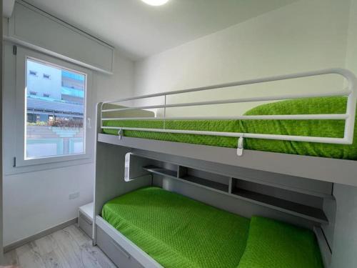 a green bunk bed with a window in a room at Baja Moderno Trilocale vicino al mare in Bibione