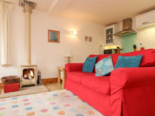um sofá vermelho numa sala de estar com lareira em Plum Cottage em Colebrooke