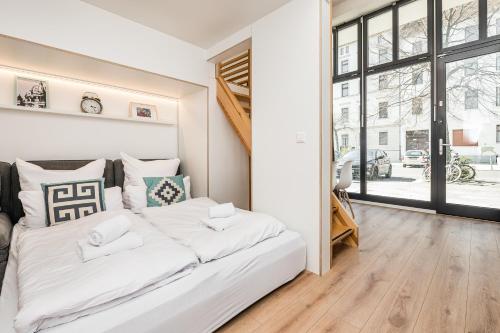 un lit blanc dans une chambre avec une grande fenêtre dans l'établissement Stylish New Cube Loft by Berlin-Wall-Apartments, à Berlin
