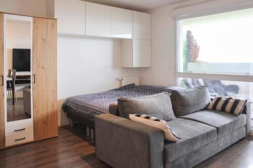 een woonkamer met een bank en een bed bij Brand new studio with an open view on Paris in Arcueil