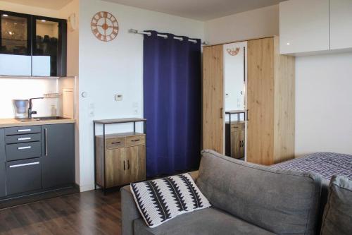 een woonkamer met een bank en een keuken bij Brand new studio with an open view on Paris in Arcueil