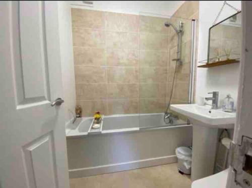 a bathroom with a white tub and a sink at SeaBright; one bed apartment with garden and parking in Mundesley