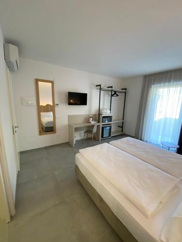 a white bedroom with a large bed and a desk at B&B Garda Home in Nago-Torbole