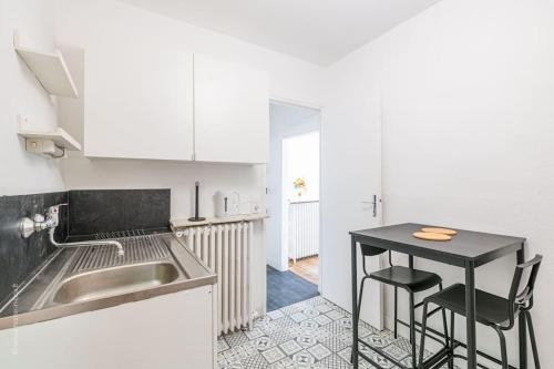une cuisine avec un évier et une table avec deux chaises dans l'établissement L'Orée Proche centre ville, à Saint-Germain-en-Laye
