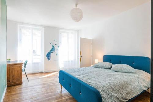 une chambre avec un lit bleu dans une pièce blanche dans l'établissement L'Orée Proche centre ville, à Saint-Germain-en-Laye