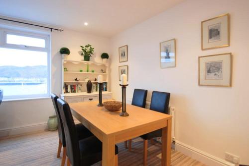 uma sala de jantar com uma mesa de madeira e cadeiras em Estuary View Apartment em Deganwy