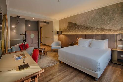 ミラノにあるNH コレクション ポルタ ヌオーヴァの白いベッドとデスクが備わるホテルルームです。