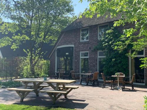 een picknicktafel en stoelen voor een gebouw bij De Loeghoeve in Anderen