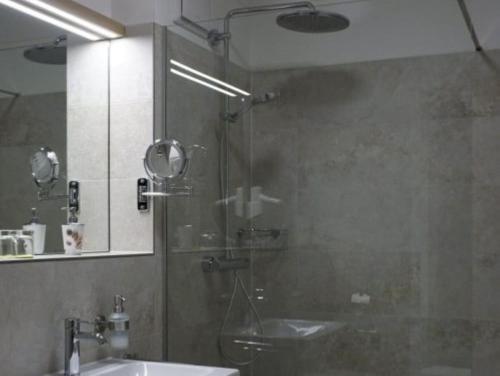 uma casa de banho com um chuveiro, um lavatório e um espelho. em Gasthof Weißes Ross em Iphofen