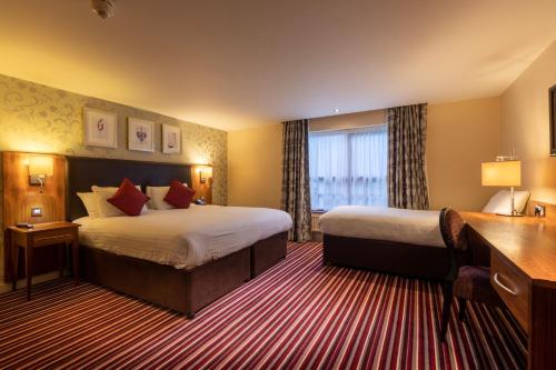 a hotel room with two beds and a desk at Gloucester Robinswood Hotel, BW Signature Collection in Gloucester