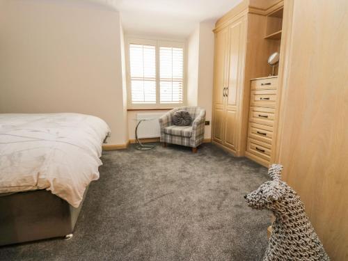 a bedroom with a bed and a chair and a dresser at The Anvil in Broughton in Furness