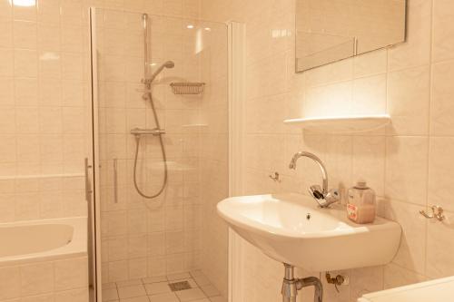 a white bathroom with a shower and a sink at Duinerei Groote Keeten in Callantsoog
