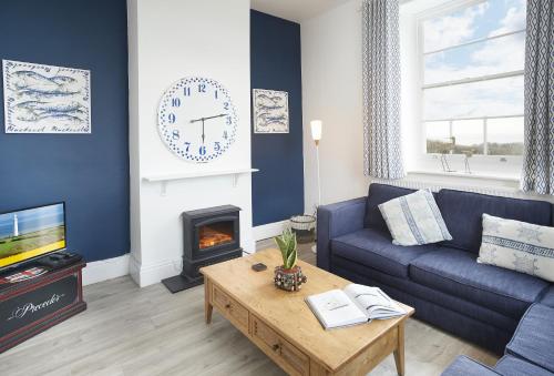 a living room with a couch and a clock on the wall at Ariel in Marcross