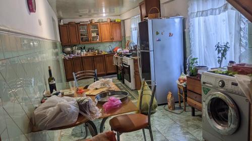 a kitchen with a table and a refrigerator at Cosy Guesthouse in Tsqaltubo