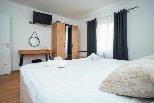 um quarto com uma cama branca e uma secretária em Holiday Home Lu em Grkavešćak