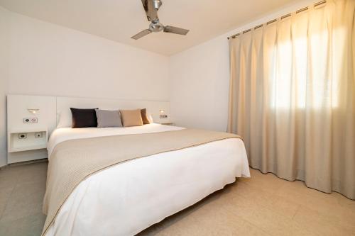 a white bedroom with a large bed and a window at Ses Eufabietes Apartments & Restaurant in Sant Francesc Xavier