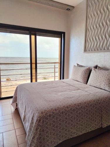 een slaapkamer met een bed en uitzicht op de oceaan bij clapotis in El Jadida