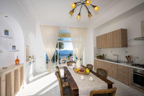 una cucina e una sala da pranzo con tavolo e frutta di YourHome - Villa Aldo Marino a Positano